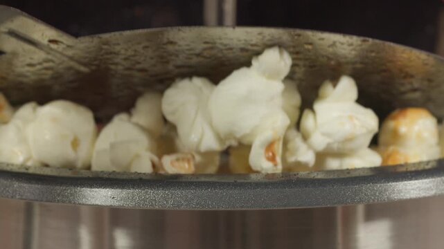 Extreme macro footage of popcorn kernels popping and expanding into crispy popcorn. Detailed food texture with golden colors and dynamic motion captured in 4K for snack, cinema and food concept.