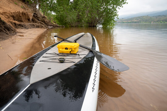 touring stand up paddleboard with waterproof box,  safety leash and paddle on a calm Horsetooth Reservoir in summer scenery in northern Colorado