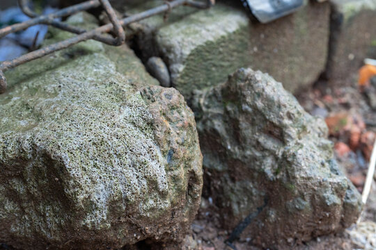 Close-Up Of Rough Porous Stones Near Metal Grating