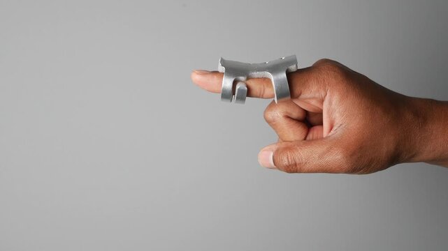Hand using metal tool for finger support in simple setting
