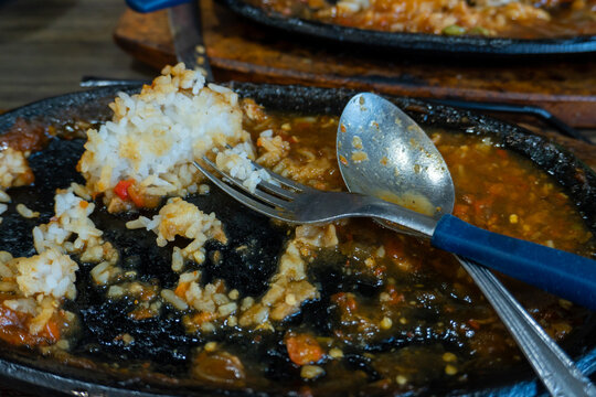 Partially Eaten Rice And Sauce On A Black Cast Iron Plate