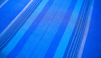 Obraz premium Close-up diagonal perspective view of traditional Indonesian woven sarong fabric with selective focus on blue striped patterns