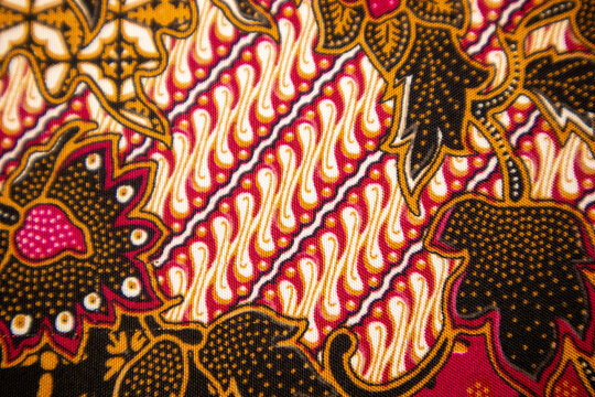 Close-up macro view of traditional Indonesian batik fabric featuring classic diagonal parang rusak motifs combined with floral ornaments
