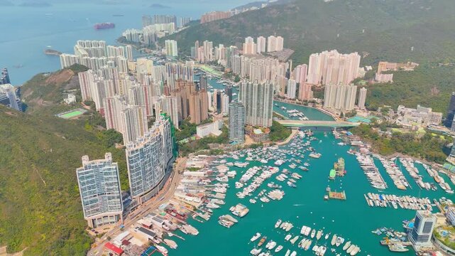 Harbor view with traditional fishing boats and modern yachts in front of tall residential skyscrapers in Hong Kong Kellet Bay