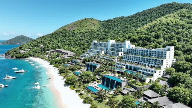 Luxurious resort with cascading pools and yachts on a turquoise bay, framed by lush green mountains