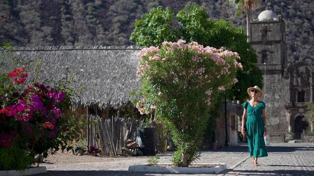 A senior woman explores the San Javier Mission in Baja California Sur, Mexico during sunrise and enjoys the beautiful desert landscape