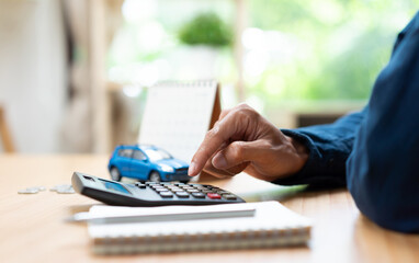 Auto loan calculation and vehicle financing concept with calculator, car model, coins, and payment schedule, representing budgeting, loan repayment, ownership costs, and personal financial planning. © Father_Studio