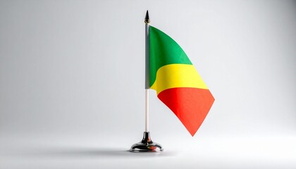 Naklejka premium A small Republic of the Congo flag on a silver stand with a fleur‑de‑lis finial, symbolizing national pride and diplomatic formality.