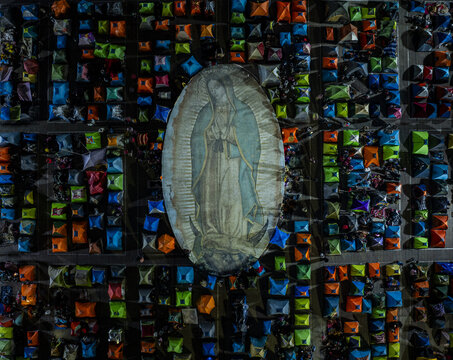 Aerial view of a large image of Our Lady of Guadalupe surrounded by a grid of colorful tents at night in Mexico.