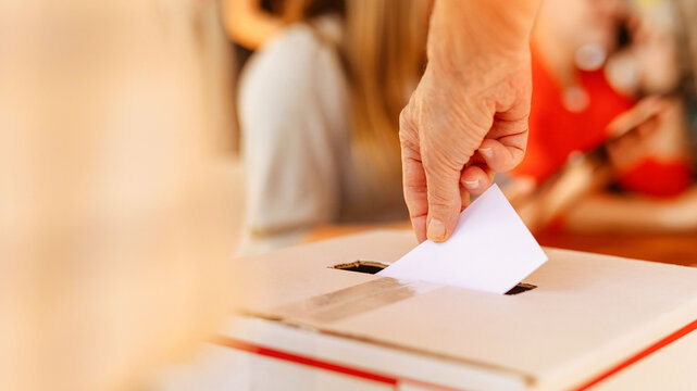 Hand dropping ballot into voting box during election