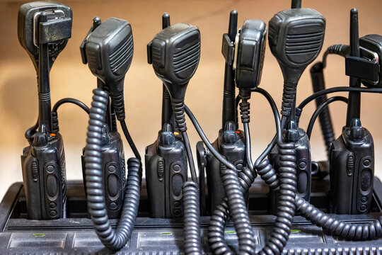 Two-Way Radios in Charging Station Ready for Emergency Communication, Close-up photograph of multiple portable two-way radios in a charging station. Communication equipment used by emergency services,