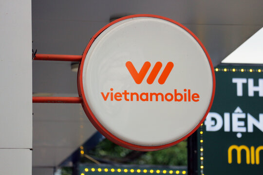 DANANG, VIETNAM - JANUARY 22, 2026: A daytime view of a round outdoor projecting blade sign with the Vietnamobile corporate logo and name mounted on a building.