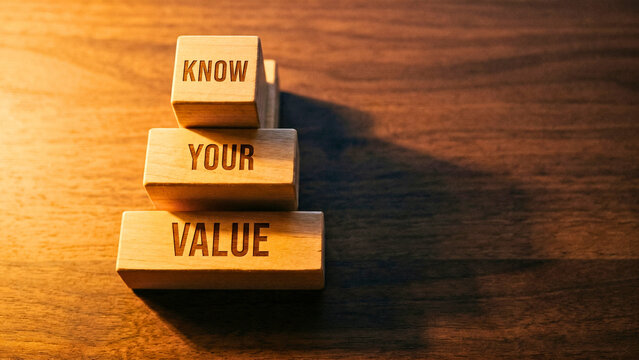 Three-row stacked wooden blocks spelling Know Your Value on dark walnut surface vertical, self-worth professional concept, career confidence strategy, recognizing talent business