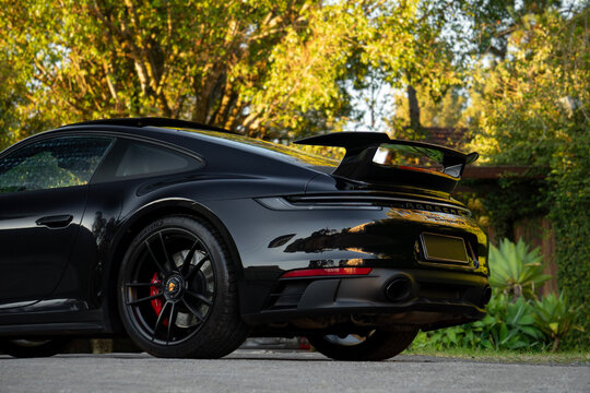 Black Porsche 911 Carrera GTS rear end low angle view, Sports car outdoor shot near nature