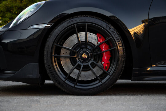 Black Porsche 911 Carrera GTS front wheel closeup, Luxury Sports car external detail outdoors