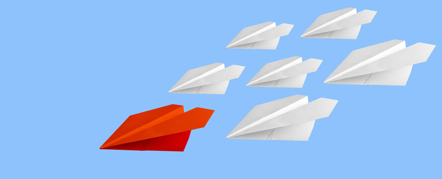 Red paper airplane leading formation of white paper airplanes across blue background