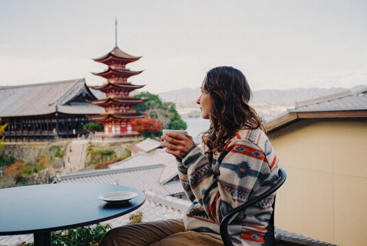Woman drinking coffee in the rooftop cafe with view of Miyajima island