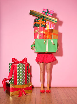 woman holds a tower of wrapped presents obscuring her bo