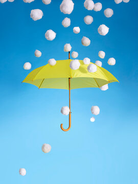 A yellow umbrella hovers in mid air in a shower of snowballs