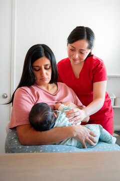 Midwife guiding mother with breastfeeding