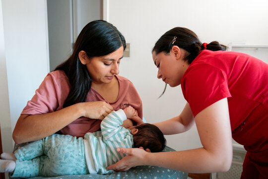 Midwife assisting mother with breastfeeding