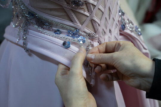 The designer is sewing a pink evening gown (stock photo)