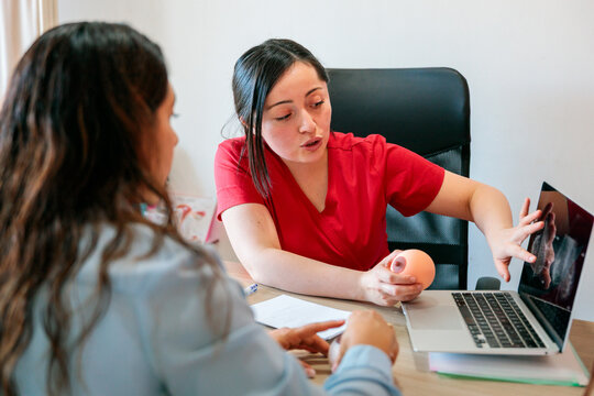 Healthcare professional showing mammogram results on laptop