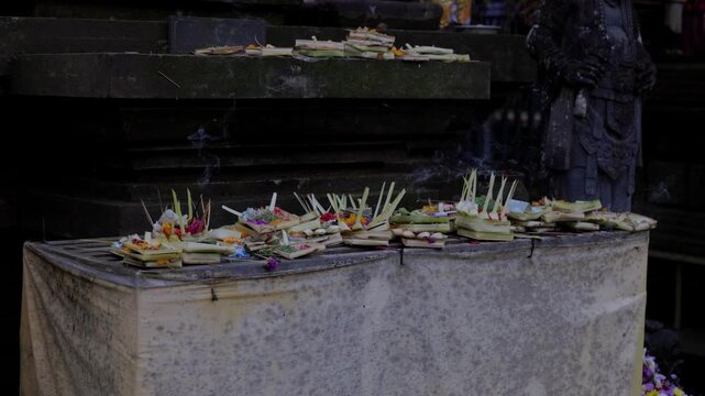 Canang Sari offerings at Bali Hindu temple. Incense is smoking. Location: Bali.