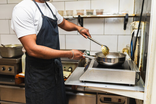 Close up of chef stir frying in commercial pan
