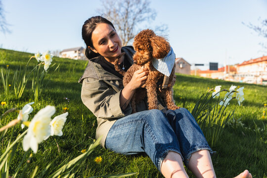 Asian woman and dog sitting on grass with flowers