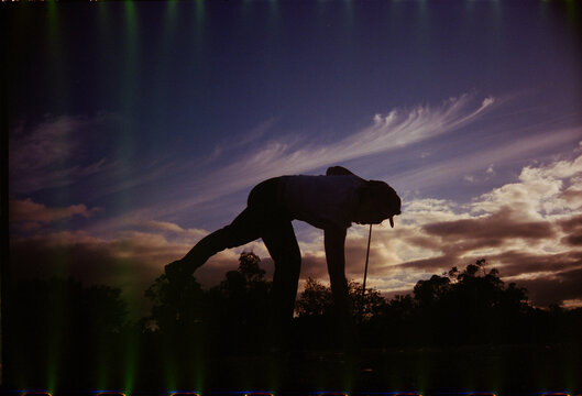 Golfer at sunset picking up ball at last hole on course 