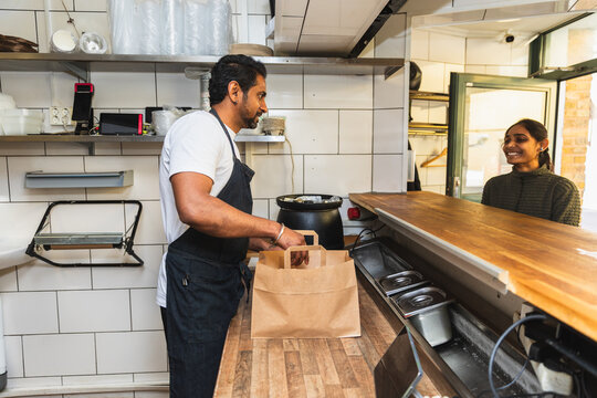 Restaurant worker packing takeaway bag for customer