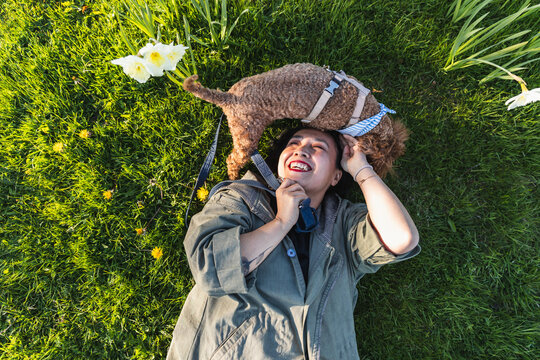 Happy woman lying on grass with pet dog