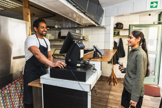 Indian restaurant owner at POS checkout with customer