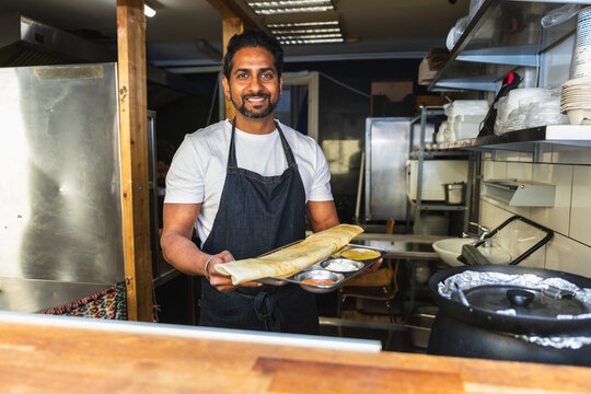Smiling Indian chef presenting freshly made dosa