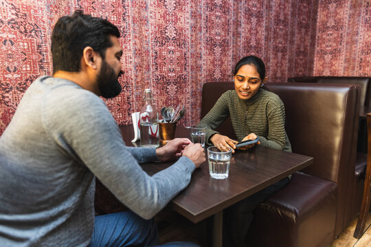 Indian couple dining and using phone at table