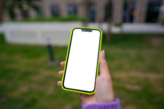 Holding a phone in a green outdoor space