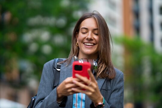 Smiling person using a phone in a city setting