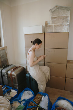 Woman scrolling phone and preparing for a house move