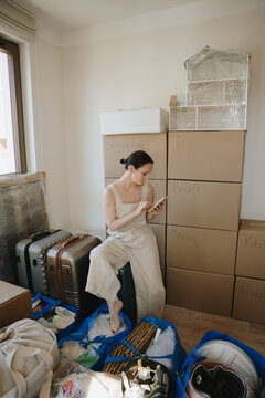Woman scrolling phone and preparing for a house move