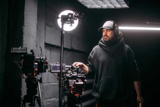 The director of photography holds a camera in his hands on the set in the pavilion. A professional videographer films a movie, commercial or TV series in a studio.