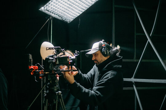 The director of photography holds a camera in his hands on the set in the pavilion. A professional videographer films a movie, commercial or TV series in a studio.