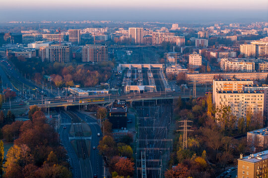 Aerial view of Dworzec Gdanski railway station with train tracks and platforms surrounded by autumn trees and residential buildings in Warsaw, Masovian Voivodeship, Poland.