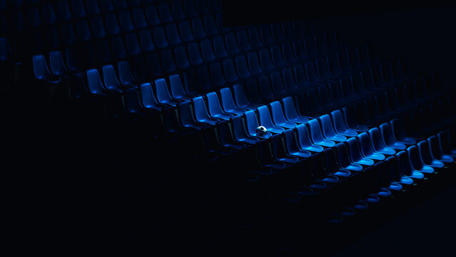 Soccer ball rests on blue stadium seats in an empty arena
