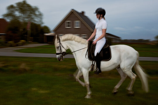 Woman Riding a White Horse Near a House in the Countryside
