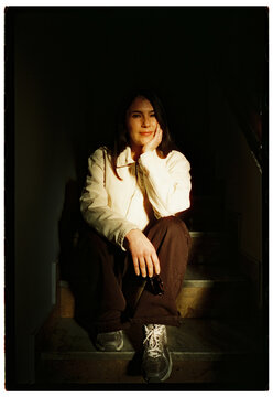Young woman sitting on stairs in dramatic sunlight
