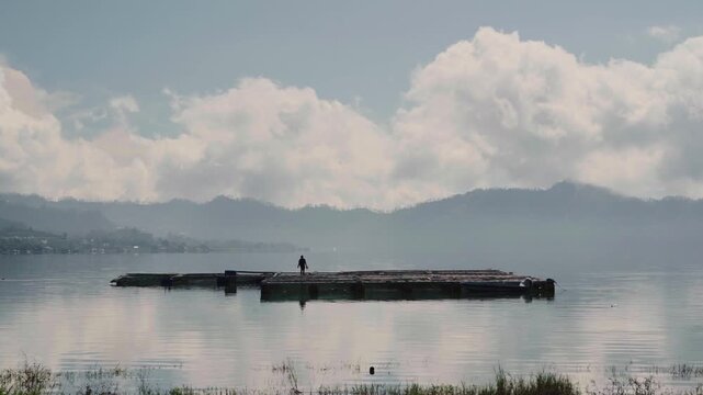 Scenic view of Batur lake. Isolated by cloudy sky. There is fisherman and tilapia fish or ikan mujaer's cage in the middle of the lake. 4K Horizontal timelapse footage. Tavel, nature concept