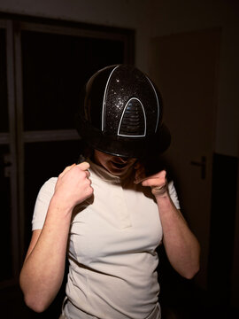 Person Puts on a Helmet in a Dimly Lit Space at Night