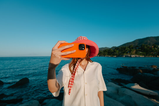 woman taking photo with cellphone on the beach