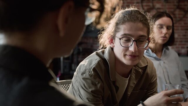 Over the shoulder shot of Caucasian teenager with glasses sharing story during group therapy session with people. Clip for mental health awareness campaigns and youth counseling services
